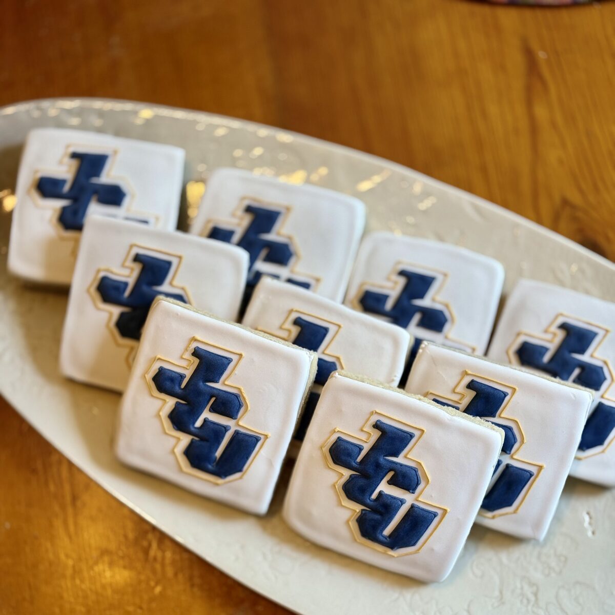 Square frosted logo cutout cookies on a white serving plate.